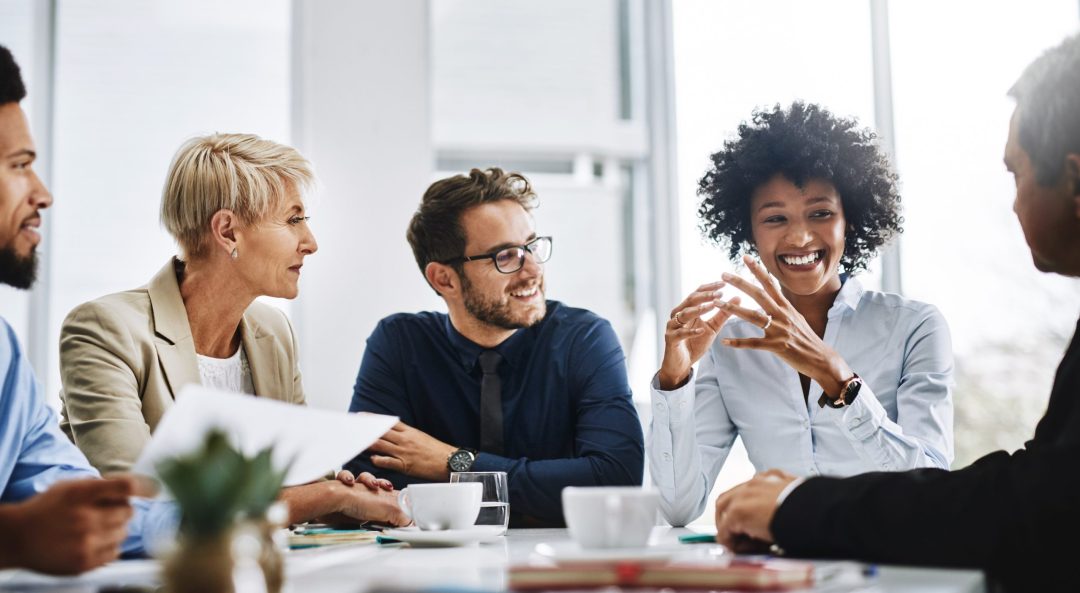 Group of businesspeople around a table, smiling.