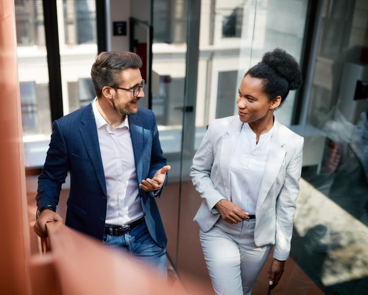 Happy colleagues talking while walking up the stairs in office.